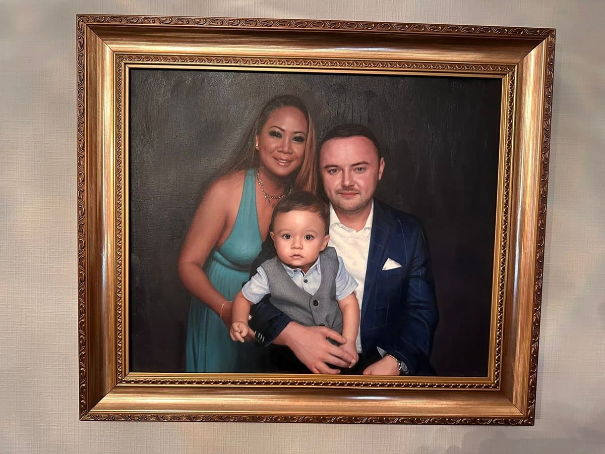 A family portrait hand-painted in oil on canvas, hanging framed on a wall